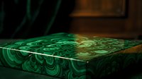 Luxury malachite green decorative box with swirling stone pattern, gold trim accents, elegant surface texture in moody dark interior setting.