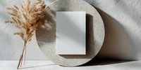 Minimalist composition with blank white card on round concrete stand and dried pampas grass against textured wall. Modern aesthetic for branding mockups.
