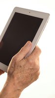 Senior man holding white tablet device with blank black screen against white background, displaying technology usage by older adult.