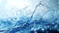 Dynamic water splash with crystalline droplets against light blue background, featuring flowing liquid motion and sparkling water particles in macro photography.