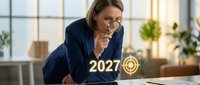 Middle-aged Caucasian woman, business professional, wearing navy blazer and glasses, leaning forward at desk with thoughtful expression, hand near face, contemplating glowing 2027 holographic projection on table with plants in background.