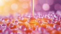 Golden honey dripping onto surface with water droplets creating beautiful bokeh light effects in warm pink and orange tones for culinary and wellness designs.