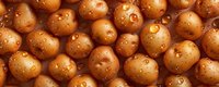 Fresh raw potatoes with water drops on brown surface, top view macro photography. Natural organic vegetables background pattern for food industry.