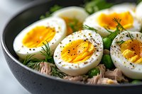 Soft boiled eggs with runny yolks served on fresh greens and herbs in dark bowl. Healthy breakfast or lunch meal with protein and vegetables.