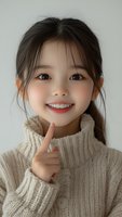 Young Asian woman in cozy cream turtleneck sweater showing cheerful expression with finger gesture against light background. Soft natural makeup and casual hairstyle.