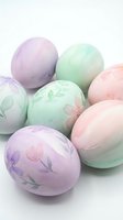 Pastel colored Easter eggs with delicate floral patterns in soft pink purple and green hues isolated on white background for spring holiday decorations.