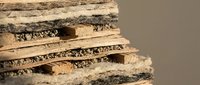 Stack of natural cork bark sheets with rough textured surface for crafting and industrial applications on neutral background.