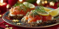 Smoked salmon canapes with cream cheese, dill, and lemon slices on dark bread, served on festive holiday table with bokeh lights and decorations.