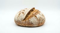 Freshly baked artisan sourdough bread loaf with golden crust and rustic texture isolated on white background for bakery and food design projects.