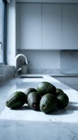 Fresh ripe avocados on marble kitchen counter in modern minimalist home interior with natural lighting for healthy cooking and meal preparation.