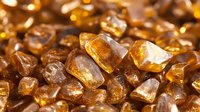 Amber-colored rock sugar crystals in macro shot showing natural crystalline structure with warm golden light illumination and reflective surfaces.