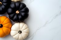 Orange, black and white decorative pumpkins arranged on white marble background with copy space, modern minimal autumn holiday composition.