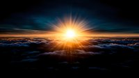 Dramatic sunrise over dark clouds with vibrant sunburst breaking through stormy sky, aerial view showing majestic natural phenomenon above cloudscape.