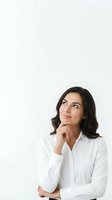 Young Hispanic businesswoman in white shirt looking up thoughtfully with hand on chin, isolated on white background for professional design use.