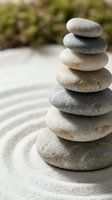 Balanced stack of smooth river stones on raked sand creating zen garden meditation space for mindfulness and relaxation practices.