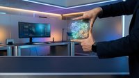 Businessman holding glowing digital brain hologram in modern office workspace with computer monitor, representing artificial intelligence, innovation, and technology solutions for business growth.