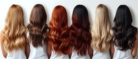 Women with different hair colors from blonde to black showing long wavy hairstyles, wearing white tops, back view. Hair color palette demonstrates natural and dyed shades.