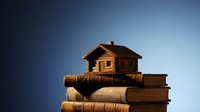 Miniature wooden house model sitting on stack of old leather-bound books against blue gradient background representing real estate education and property investment.