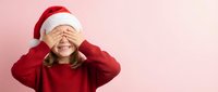 Young woman in red sweater and Santa hat covering eyes with hands in playful gesture against pink background for holiday marketing and festive campaigns.