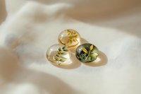 Three golden resin spheres with pressed botanical leaves creating elegant shadows on cream fabric surface for luxury spa and wellness branding.