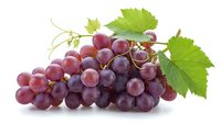 Fresh red grapes cluster with green leaves isolated on white background. Organic fruit harvest for healthy eating, wine making and culinary use.