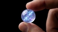 Glowing blue digital sphere held between human fingers against dark background, representing technology, innovation, and digital connectivity for business concepts.