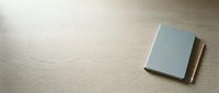 Closed notebook with blank cover on wooden surface, top view for design and branding projects.
