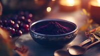 Dark purple acai berry powder in ceramic bowl with wooden spoon on rustic table, warm bokeh lights background, superfood and healthy eating concept.