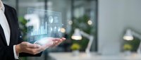 Businessperson holding a glowing holographic dashboard with charts and graphs, representing data analytics and digital business intelligence.