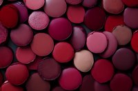 Collection of red and burgundy makeup blush and eyeshadow pans arranged as a flat lay background for beauty and cosmetics design.
