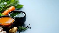 Fresh homemade vegetable soup in black ceramic bowls with carrots, mushrooms and herbs on light blue background, healthy eating concept. Food photography.