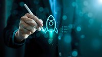 Businessman drawing glowing rocket icon with digital pen on futuristic blue background. Business startup launch concept for innovation and entrepreneurship growth.