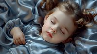 Peaceful sleeping toddler girl with rosy cheeks lying on silky blue bedding, soft natural lighting creates dreamy atmosphere for childhood, parenting and lifestyle designs.