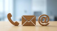 Wooden contact icons phone envelope and email symbol on desk representing customer service and business communication channels.