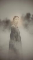 Young Asian man in flowing robe standing in misty atmospheric landscape with soft ethereal lighting and dreamy fog effects for spiritual meditation concepts.