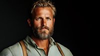 Confident middle-aged Caucasian man with blonde hair and full beard wearing casual shirt against dark background for professional headshot photography.