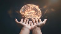 Glowing brain floating above open hands representing mental health, psychology, neuroscience, artificial intelligence, creativity and human consciousness concepts.