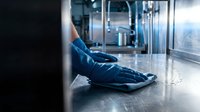 Healthcare worker in blue scrubs resting on hospital floor during break, medical professional exhaustion and burnout concept for wellness campaigns.