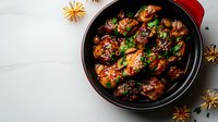 Glazed chicken wings in sweet and spicy Asian sauce garnished with sesame seeds and fresh herbs, served in red ceramic bowl on marble background with star anise decoration.