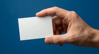 Hand holding blank white business card on blue background for mockup design and branding presentation.