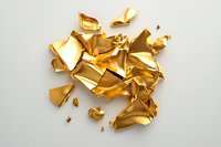 Crumpled pieces of shiny gold foil scattered on white background creating abstract luxury composition with dramatic shadows and metallic texture.