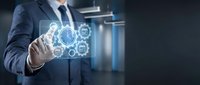 Businessman in dark suit and tie touching glowing digital gear icons with interconnected symbols representing technology, innovation, and industrial processes in modern office setting.