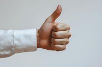 Male hand with medium skin tone giving thumbs up gesture wearing white shirt sleeve, isolated on neutral background for approval, success, and positive feedback concepts.