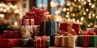 Festive holiday gifts wrapped in colorful paper with ribbons and bows, stacked together against blurred Christmas tree lights background.