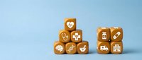 Orange wooden cubes with white medical healthcare icons arranged on light blue background for hospital clinic pharmacy design concepts.