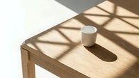 Wooden table with white ceramic mug in sunlight casting geometric shadows, minimalist interior design setup for home decor and lifestyle content.