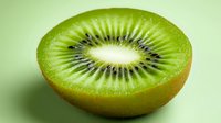 Fresh juicy kiwi fruit cut in half showing detailed seeds and flesh texture on green background, macro photography for food and healthy eating concepts.