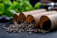 Roasted coffee beans spilling from brown paper rolls on dark background with selective focus and natural green plants, moody food photography composition.