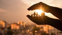 Protective hands holding family silhouettes against golden sunset sky, symbolizing care, security and love for home insurance and family protection concepts.