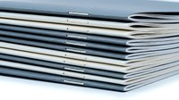 Stack of stapled notebooks or booklets piled on white surface, showcasing organization and office stationery in a clean, minimalist style.